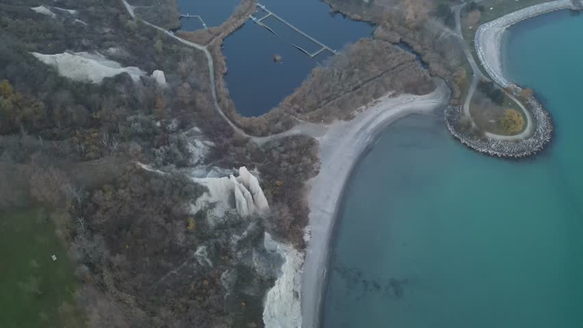 Close aerial over trees and cliffs at the Bluffs with evening sky and distant lake horizon. Use for nature or outdoor documentary segments