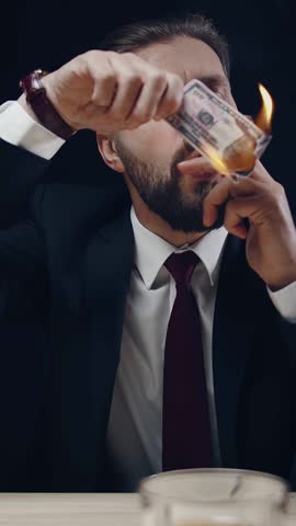A man in a suit ignites a banknote while holding a cigar. The flames dance as he expresses his thoughts on money and freedom. The setting is dimly lit, focusing on the intense moment of burning.