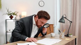 Middle-aged businessman at home office reads contract small text with magnifier finds error and shakes head no. Freelancer guy at table writes urgent fix on sticker and sets note for update this time. - Powered by Shutterstock - Get 15% off with code: PIKWIZARD15