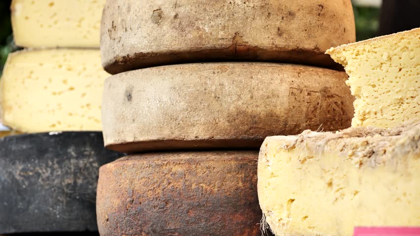 Large cheese wheels stacked at market stall