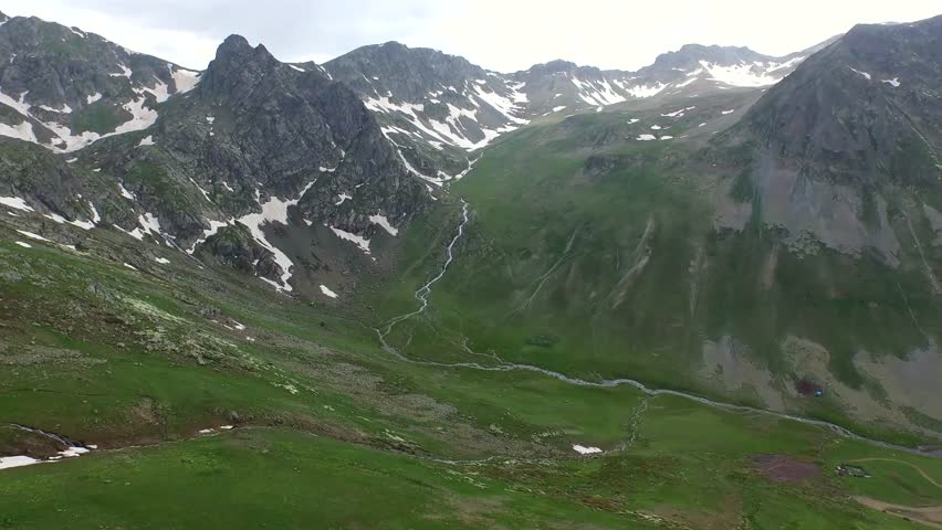 Aerial view of the Andes Mountains in South America during spring. Snow patches melt on high ridges while sunlight reveals the vast geography of the Andean landscape.