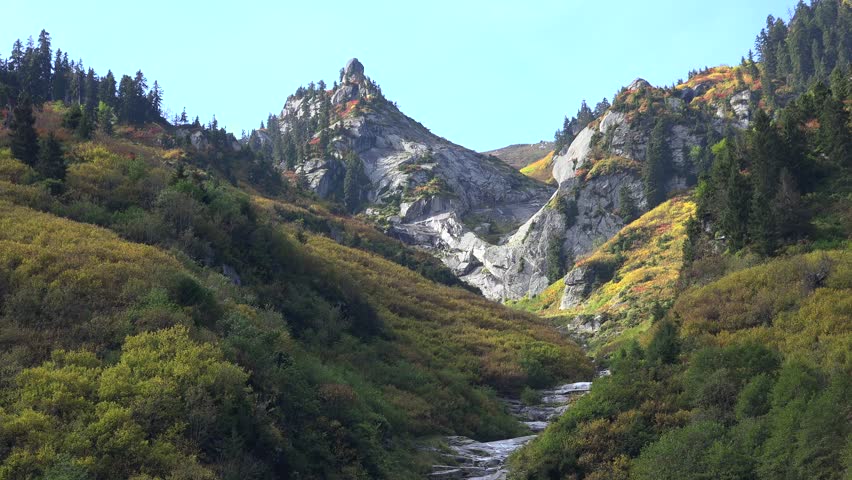 The color diversity of mixed vegetation forests in the Andes during autumn in Patagonia. Red, yellow, and orange trees blanket the mountain slopes, forming a vivid natural landscape.