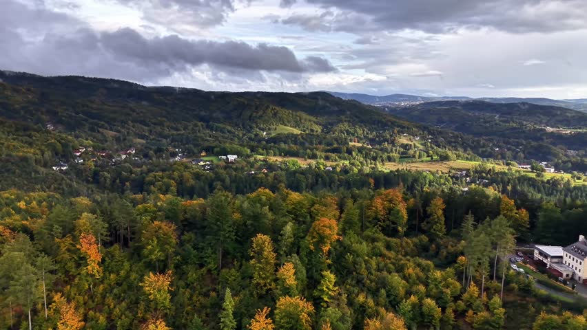 A breathtaking aerial landscape showcasing beautiful green hills, vibrant autumn foliage, and an ancient structure