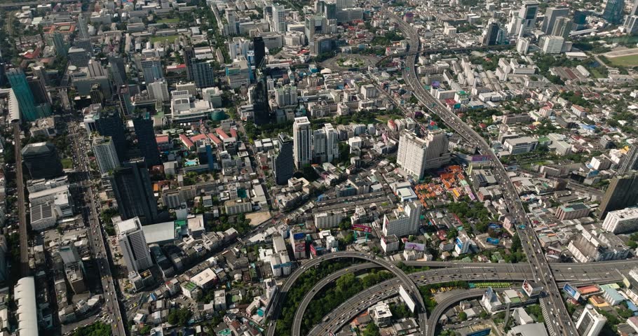 Cityscape featuring skyscrapers, highways, and green spaces under bright daylight. Bangkok, Thailand.