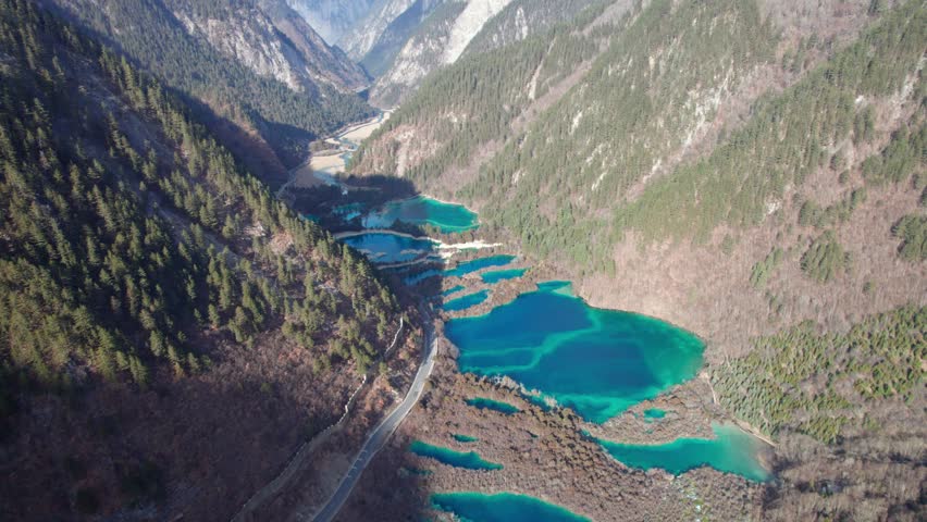 Drone view of Jiuzhaigou National Park in spring in Sichuan Province China. It features cascading waterfalls, turquoise blue lakes, and stunning mountain valleys. 4K real time footage travel concept.