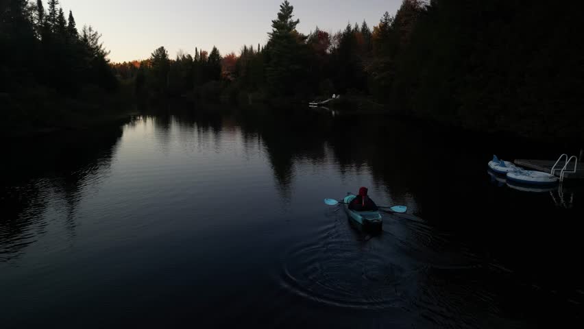 Aerial of Kayaker next to dock in Muskoka River in Bracebridge Ontario Canada at dusk