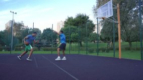 Side view of active sporty black man streetball player dribbling ball, moving past opposing defender and scoring two point field goals with layup shot while playing basketball game on outdoor court. - Powered by Shutterstock - Get 15% off with code: PIKWIZARD15