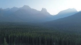 Breathtaking aerial footage captures a pine forest valley at dawn. The rising sun, hidden by the peaks, casts epic light rays through the hazy, atmospheric air. - Powered by Shutterstock - Get 15% off with code: PIKWIZARD15