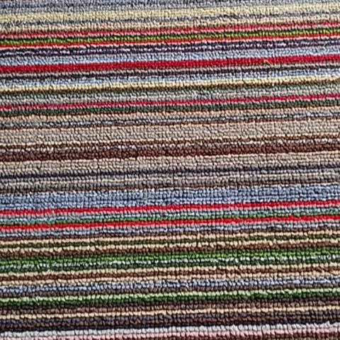 Video colorful striped carpet texture close-up. Vibrant, variegated, woven rug surface with horizontal lines in red, blue, green, and brown tones.