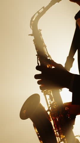 vertical slow motion silhouette of saxophonist performing on stage in warm light and smoke symbol of art of sound creative soul retro jazz night vintage mood and artistic inspiration