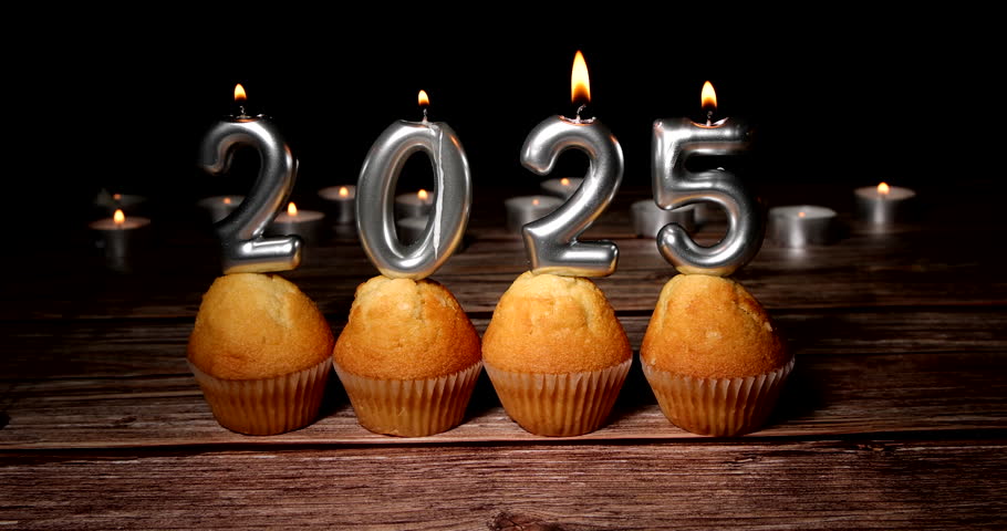 Four cupcakes topped with 2026 candles illuminate a dark background, capturing the festive transition into the new year celebration