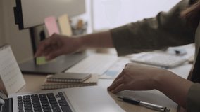 Closeup to hands of Asian businesswoman sitting at her desk and using a pen writing planning to sticky note and putting to calendar for agenda in future in office. Young female worker working at home. - Powered by Shutterstock - Get 15% off with code: PIKWIZARD15