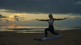 Fit woman striking warrior ii pose on yoga mat at sunrise on serene beach, woman outline accentuated by vibrant ocean horizon in background  - Powered by Shutterstock - Get 15% off with code: PIKWIZARD15