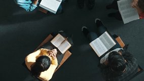 Top down view of prayers reading bible with cross on the laps while making folded hands. Aerial view of diverse people praying to god with faith, trust and hope. and sitting in circle. Symposium. - Powered by Shutterstock - Get 15% off with code: PIKWIZARD15