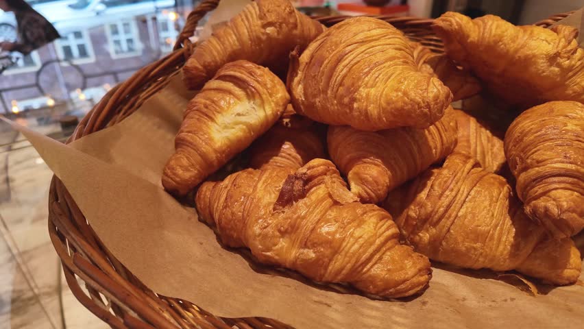 Golden fresh croissants in a wicker basket on paper delicious breakfast pastry in bakery shop