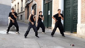 Talented group of four modern dancers in black outfits performing a synchronized and energetic contemporary dance routine on a cobblestone street in a european city. Showcasing urban culture and art - Powered by Shutterstock - Get 15% off with code: PIKWIZARD15