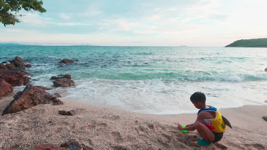 Little school boy enjoy play toy on sea beach wave summer vacation travel background