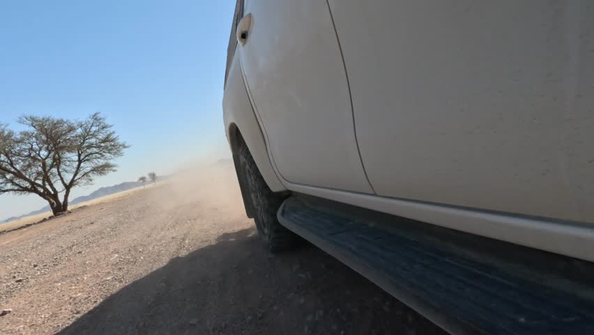 Close-up of a car wheel driving on a gravel road in Africa.