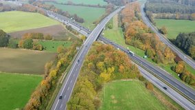Cars and trucks driving through a complex highway interchange in the german countryside surrounded by colorful autumn forests and green fields - Powered by Shutterstock - Get 15% off with code: PIKWIZARD15