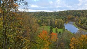 Scenic landscape of a winding river below a hillside in golden autumn forest. Birch groves and evergreens contrast as clouds drift the horizon. establishing shot for travel and nature! - Powered by Shutterstock - Get 15% off with code: PIKWIZARD15