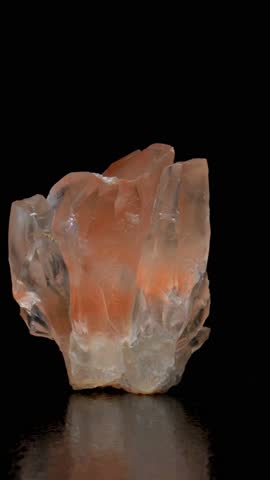 Orange Calcite crystals sample rotating slowly against a black background. Vertical
