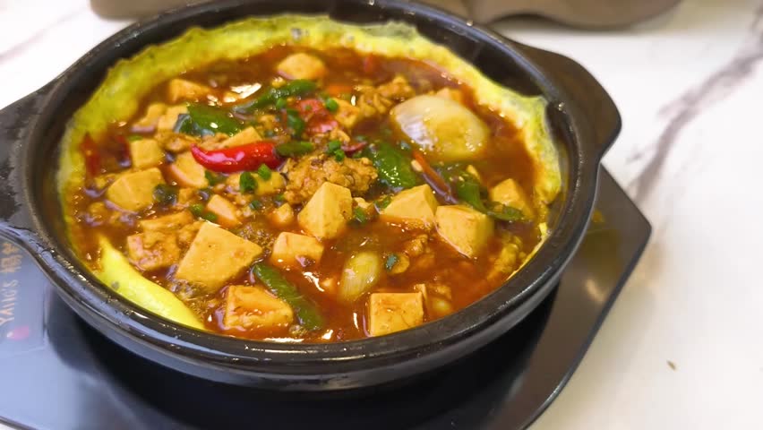 Sizzling Tofu with minced meat, chili, and egg ring in a hot clay pot.