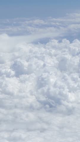 Wonderful view of cloudscape with clear blue sky from above. Beautiful panorama above white clouds as seen through window of an aircraft. A view from airplane.