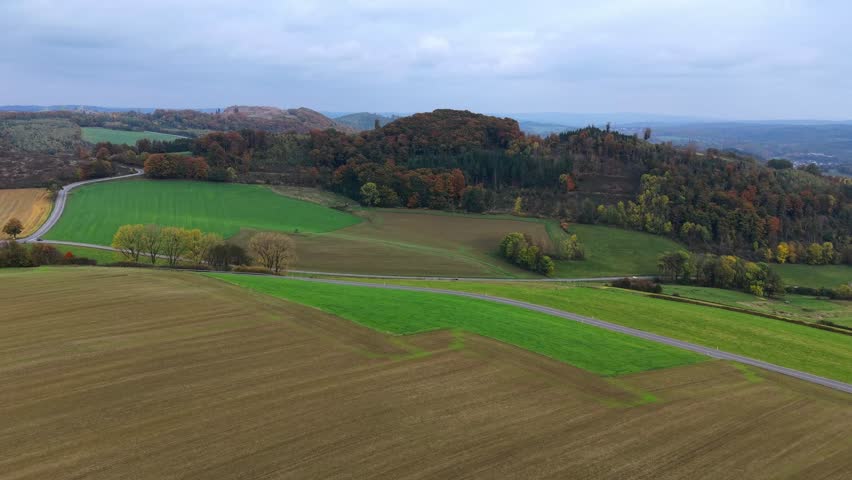 Autumnal hilly landscape: aerial view of fields and forests with road