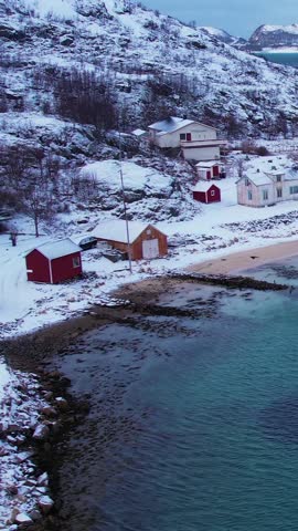 Experience the breathtaking beauty of Sommaroy islands in Troms, Norway during winter. Discover the serene beaches, icy waters, and snow-capped mountains and fishing village.
