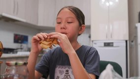 Cute Asian girl sits at kitchen table, taking a tasty bite of pancake for breakfast. Cozy home atmosphere, food and drinks around, happy childhood moment. - Powered by Shutterstock - Get 15% off with code: PIKWIZARD15