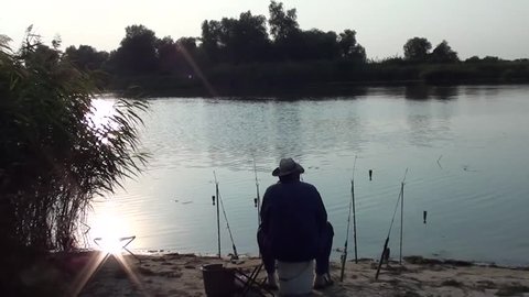 Evening fishing, five fishing rods and an angler waiting 