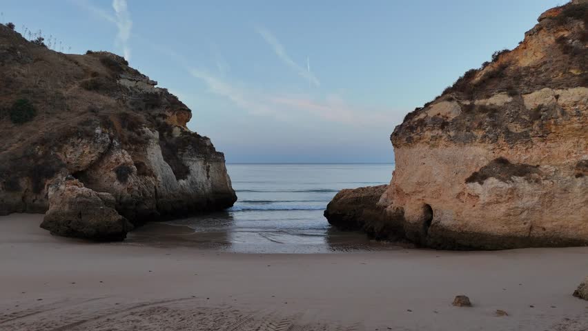 Drone Aerial view of beautiful Praia dos Tres Irmaos beach during sunrise with turquoise ocean and scenic cliffs, Portimao, Portugal.