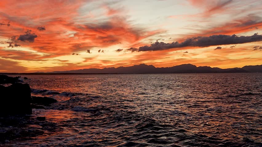 Soft evening light reflects on rocky coast and sea near Mallorca, Spain. Serene Mediterranean landscape great for vacation, nature, or relaxation-themed content