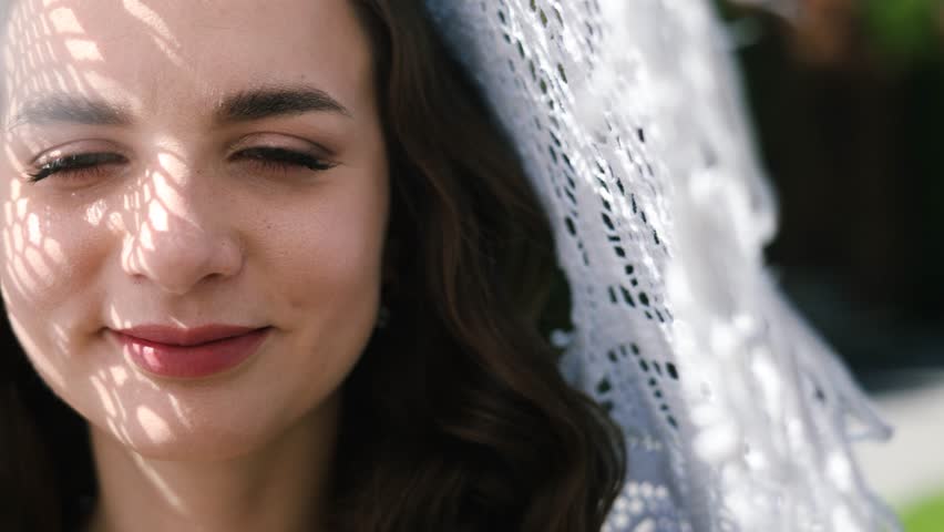Close up Portrait of a caucasian beautiful bride. Woman raises her eyes and looks into camera. She enjoys happiness. The wedding day.