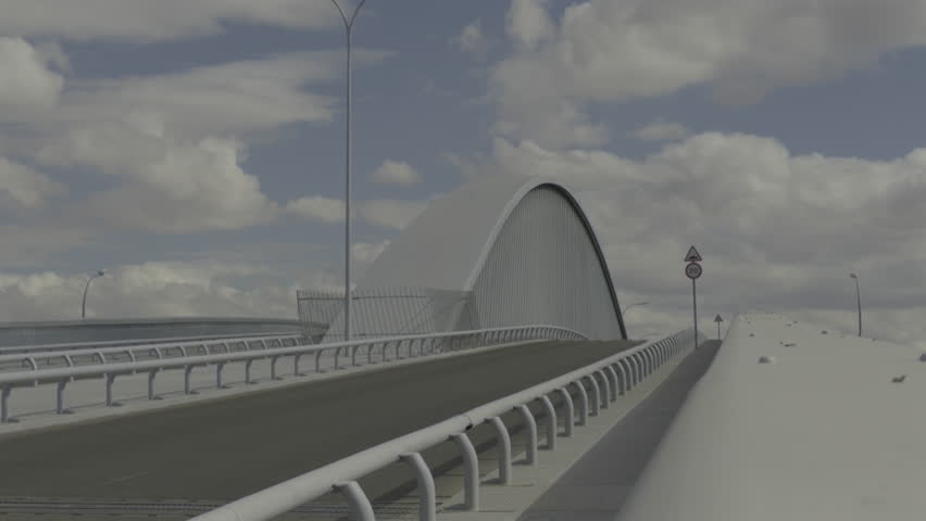 Modern gray arched bridge with an empty road leading up to it. A single car drives by on the lower highway under a cloudy blue sky