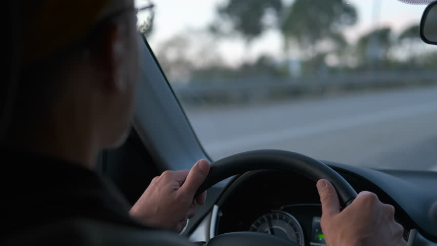 Man driving car on highway, changing lanes and overtaking. Senior man wearing glasses is driving a modern car on a highway, changing lanes, overtaking other vehicles and adjusting the steering wheel