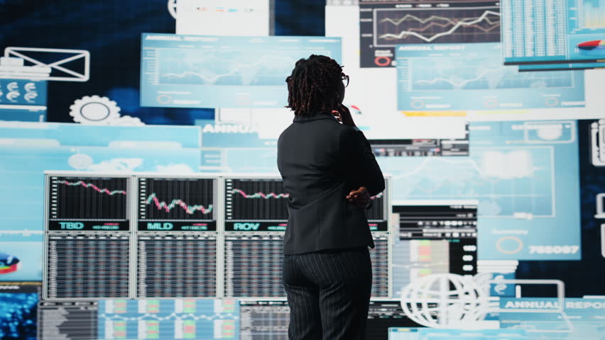 Business manager looking at graphs on digital screens, thinking how to increase company profits. African american woman reading KPI metrics projected on digital screen during decision making, camera A