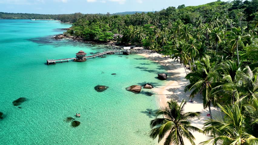 Discover the breathtaking views of Koh Kood Island, Thailand, where palm trees sway gently and turquoise waters invite relaxation. Enjoy the serene beaches and vibrant nature all around.