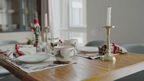 Festively decorated table setup for Christmas featuring a candle, holly themed ceramics, and holiday ornaments, capturing the essence of a warm, inviting Christmas dinner atmosphere. - Powered by Shutterstock - Get 15% off with code: PIKWIZARD15