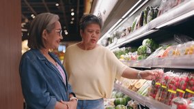 Two cheerful Asian senior women shopping for groceries in a supermarket. Attractive elderly older friends enjoy spending leisure time together, selecting products from the shelves in a modern store. - Powered by Shutterstock - Get 15% off with code: PIKWIZARD15