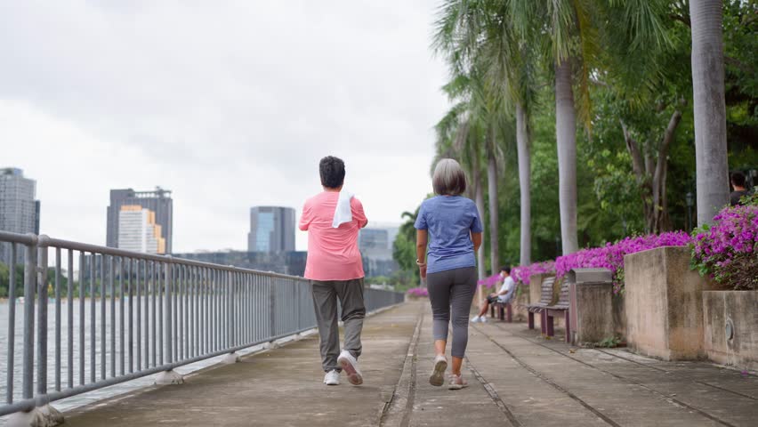 Rear view of two senior women walking exercise outdoors in modern city. Active elderly older friends wearing sportswear, enjoy healthy lifestyle, workout and fitness activity in urban park environment