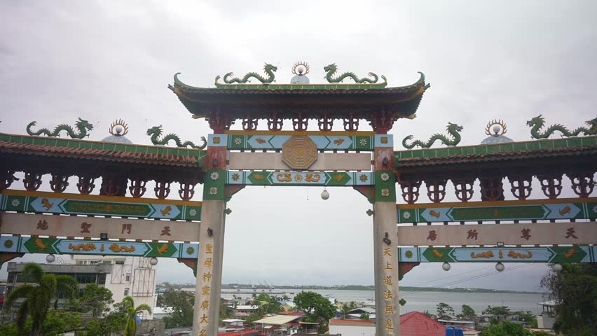 A medium static angle holds throughout, focusing on a traditional Chinese-style archway with green tiled roofs, dragon sculptures, and gold-accented pillars.