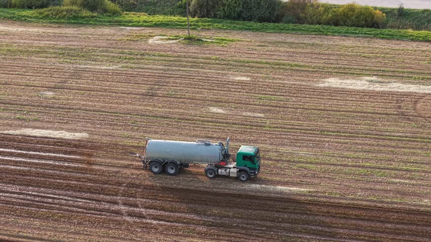 Aerial view of truck spraying manure in a large open agricultural field