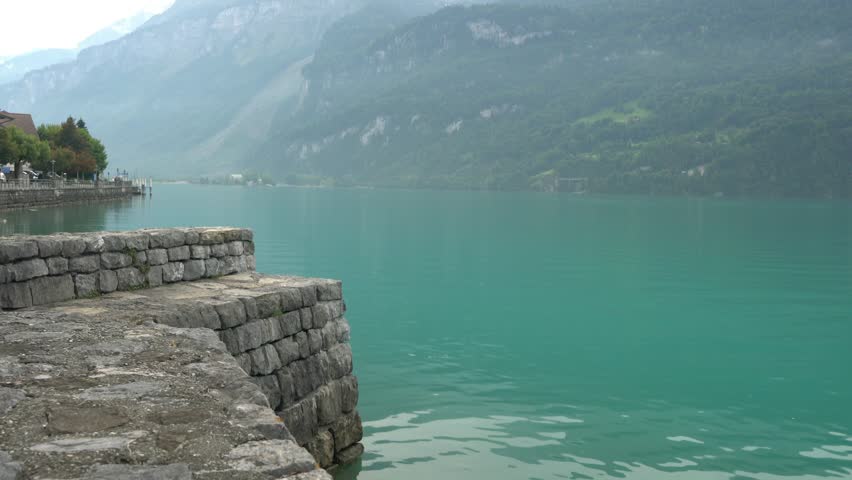 A large boat is sailing on a lake with a mountain in the background. The sky is cloudy, and the water is calm