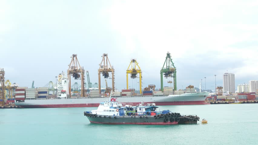 A large ship is docked at a port. The ship is surrounded by several cranes. The scene is calm and peaceful
