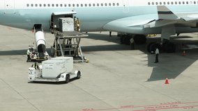 A large white airplane is being loaded with cargo. There are several people working on the plane, including a man in a yellow vest. The scene is busy and bustling, with many people - Powered by Shutterstock - Get 15% off with code: PIKWIZARD15
