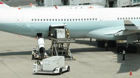 A large white airplane is being loaded with cargo. There are several people working on the plane, including a man in a yellow vest. The scene is busy and bustling, with many people - Powered by Shutterstock - Get 15% off with code: PIKWIZARD15