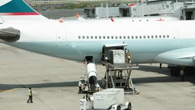 A large white airplane is being loaded with cargo. There are several people working on the plane, including a man in a yellow vest. The scene is busy and bustling, with many people - Powered by Shutterstock - Get 15% off with code: PIKWIZARD15