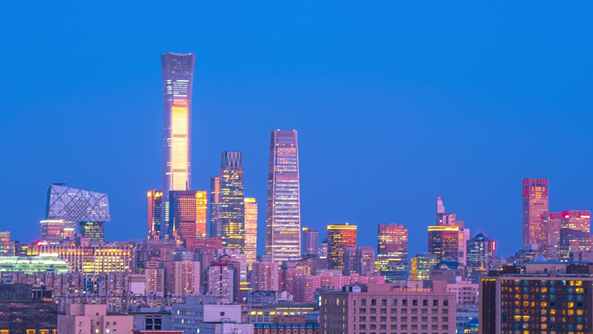 Stunning time lapse view of Beijing CBD skyline at blue hour with illuminated skyscrapers and modern architecture against vibrant twilight sky in China