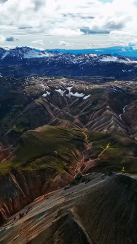 Aerial fly over snowy mountain peaks in Iceland’s highlands. Vertical shot.